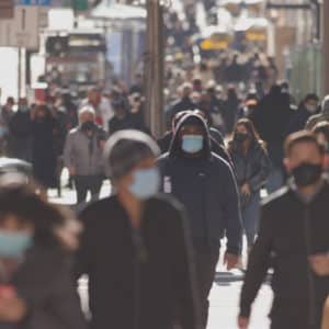 Crowd of people walking street wearing face masks during COVID-19 pandemic