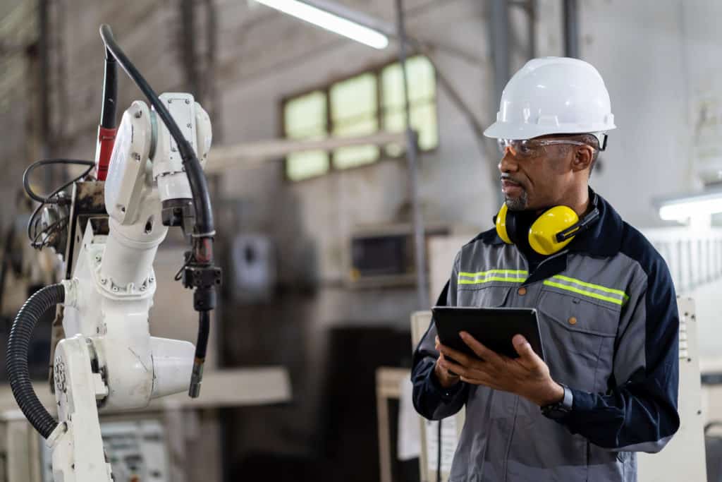 engineer using digital tablet to control a machine in factory.